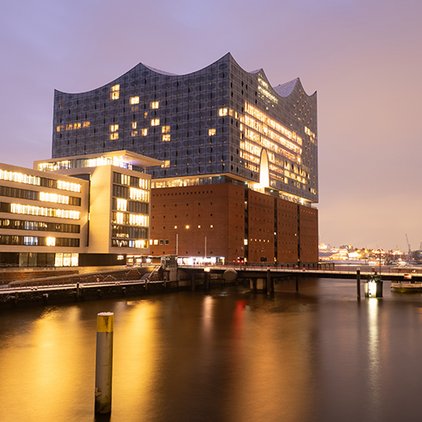Elbphilharmonie in Hamburg in der Blauen Stunde mit Langzeitbelichtung und goldenem Licht auf ruhigem Wasser